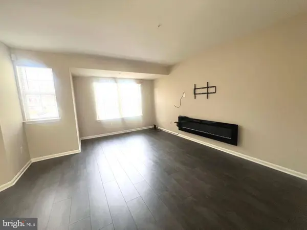 Spacious living room area with hardwood, direct sunlight