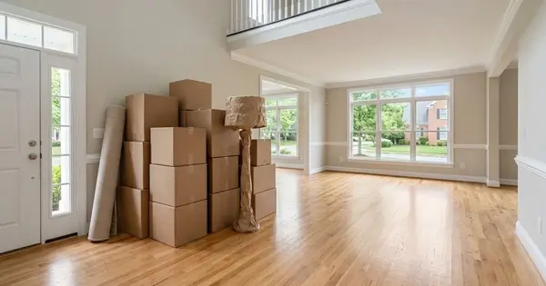 Illustration of moving boxes, a rolled rug and a wrapped floor lamp in the bright, empty entry of a Northern Virginia home, for a guide to selling an Ashburn home when relocating