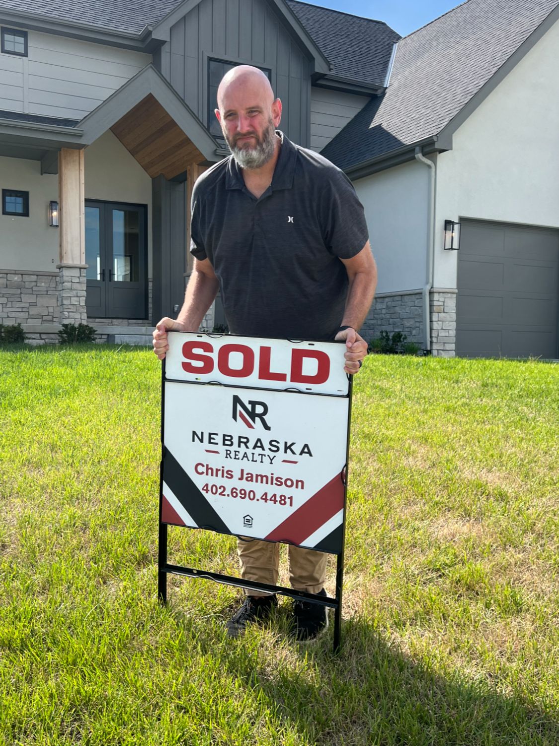 Realtor Chris Jamison placing a sold sign in the yard of an inherited home in the Omaha area