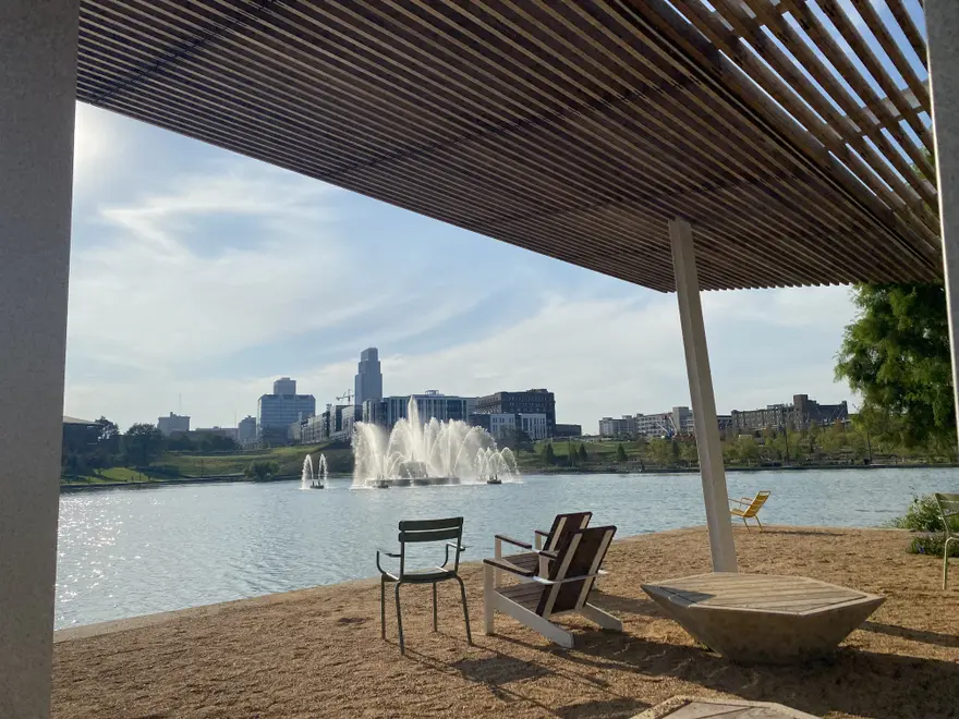The lighted fountain and lake at Heartland of America Park with the downtown Omaha skyline behind