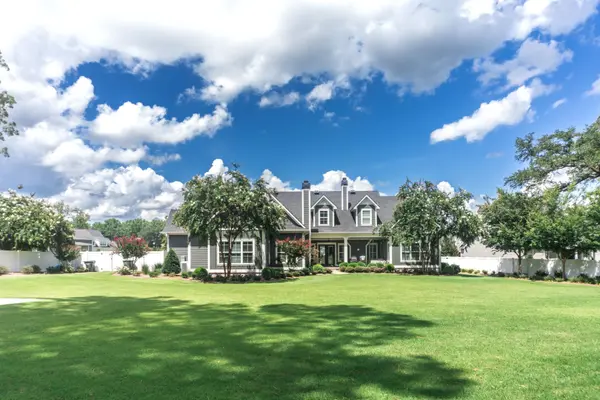 The side view of the backyard of a large gray craftsman new construction house with a landscaped yard