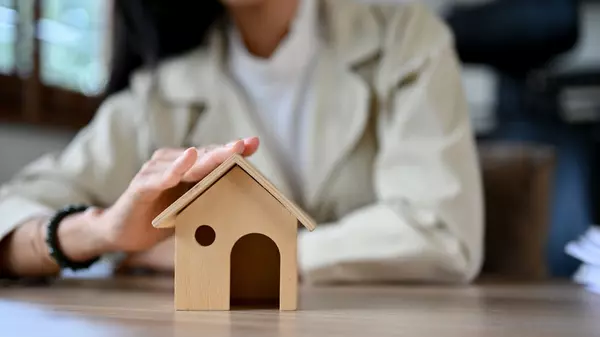 Close-up, A female real estate agent or home insurance broker touching a house's roof model