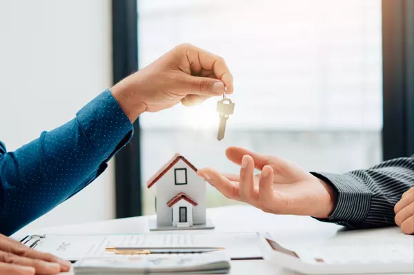 Real Estate Broker Or businessman holding white house model and house key in hand.Mortgage loan approval home loan and insurance concept.