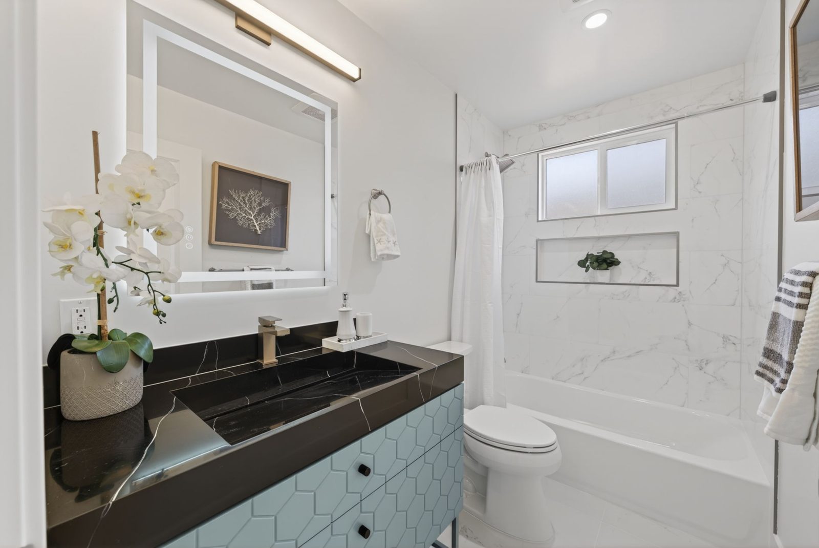 The remodeled hall bath with a statement vanity and tiled tub and shower.