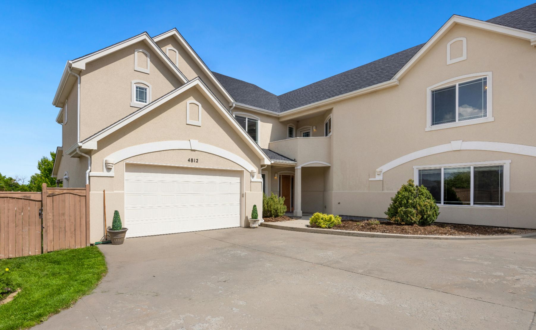 Explore this contemporary two‑story home with beige stucco exterior, dark gray roof, and spacious double garage. Located at 4812, it offers clean architectural lines, a wide driveway, and beautifully maintained front yard landscaping.