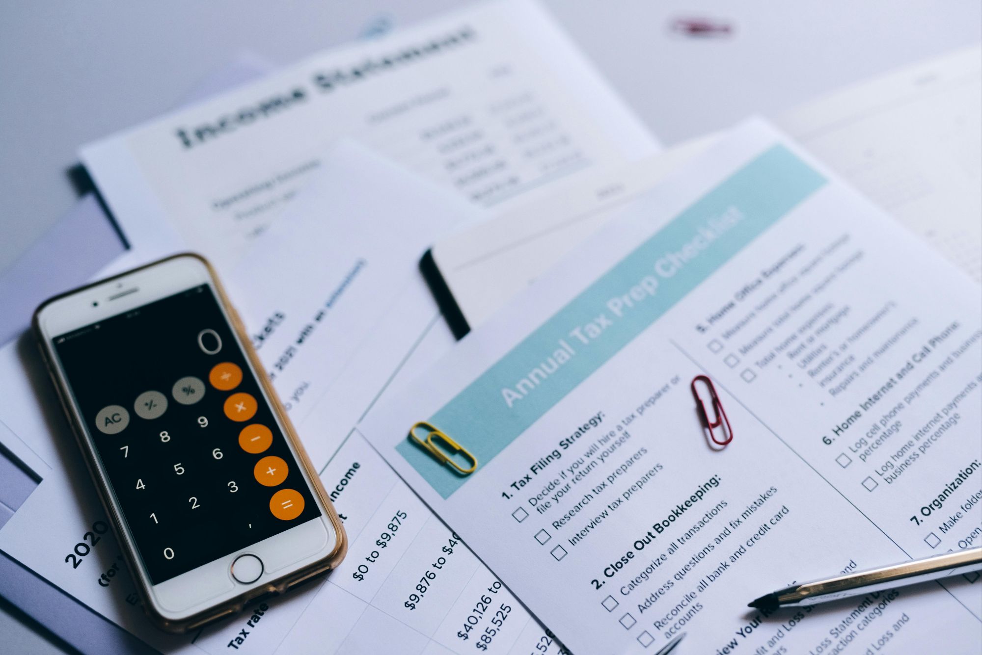Financial documents, a smartphone calculator, and tax preparation checklists on a desk, representing the financial planning required for refinancing a home in Boulder, Colorado.