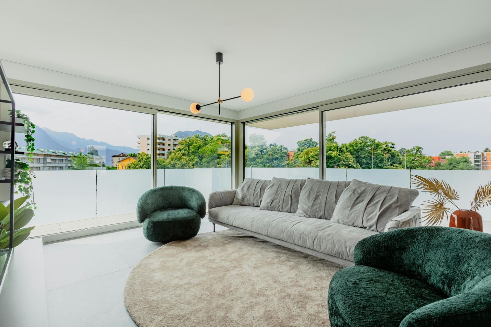 Contemporary Boulder, CO living room with floor-to-ceiling windows, plush sofa, velvet armchairs, and panoramic mountain views.