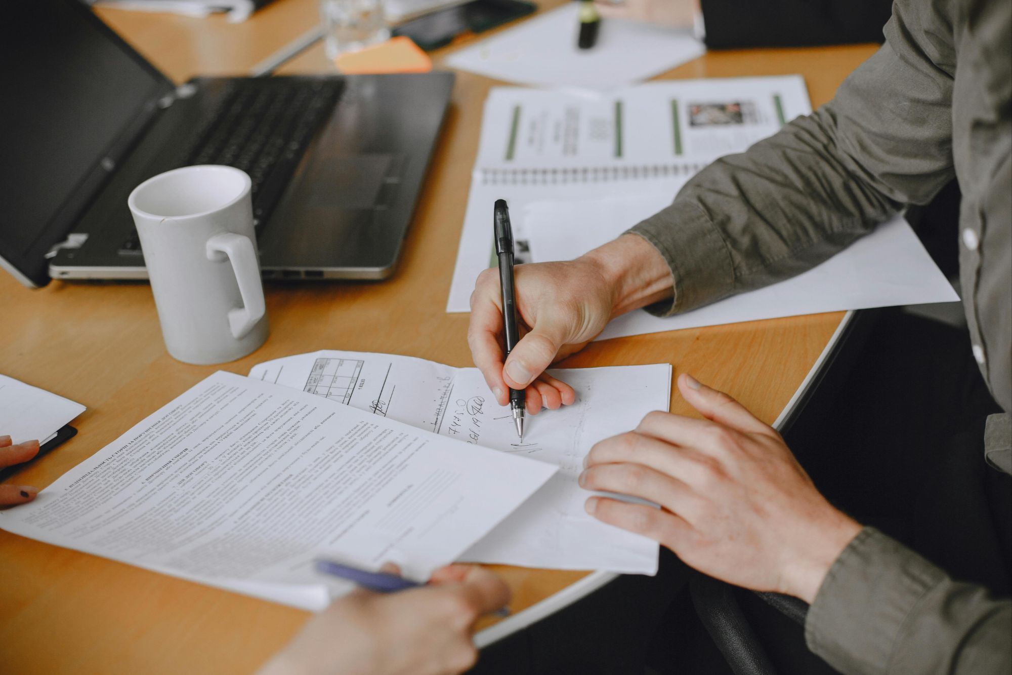 Mortgage application form on desk in Boulder, CO with calculator, pen, and two people reviewing financial details.