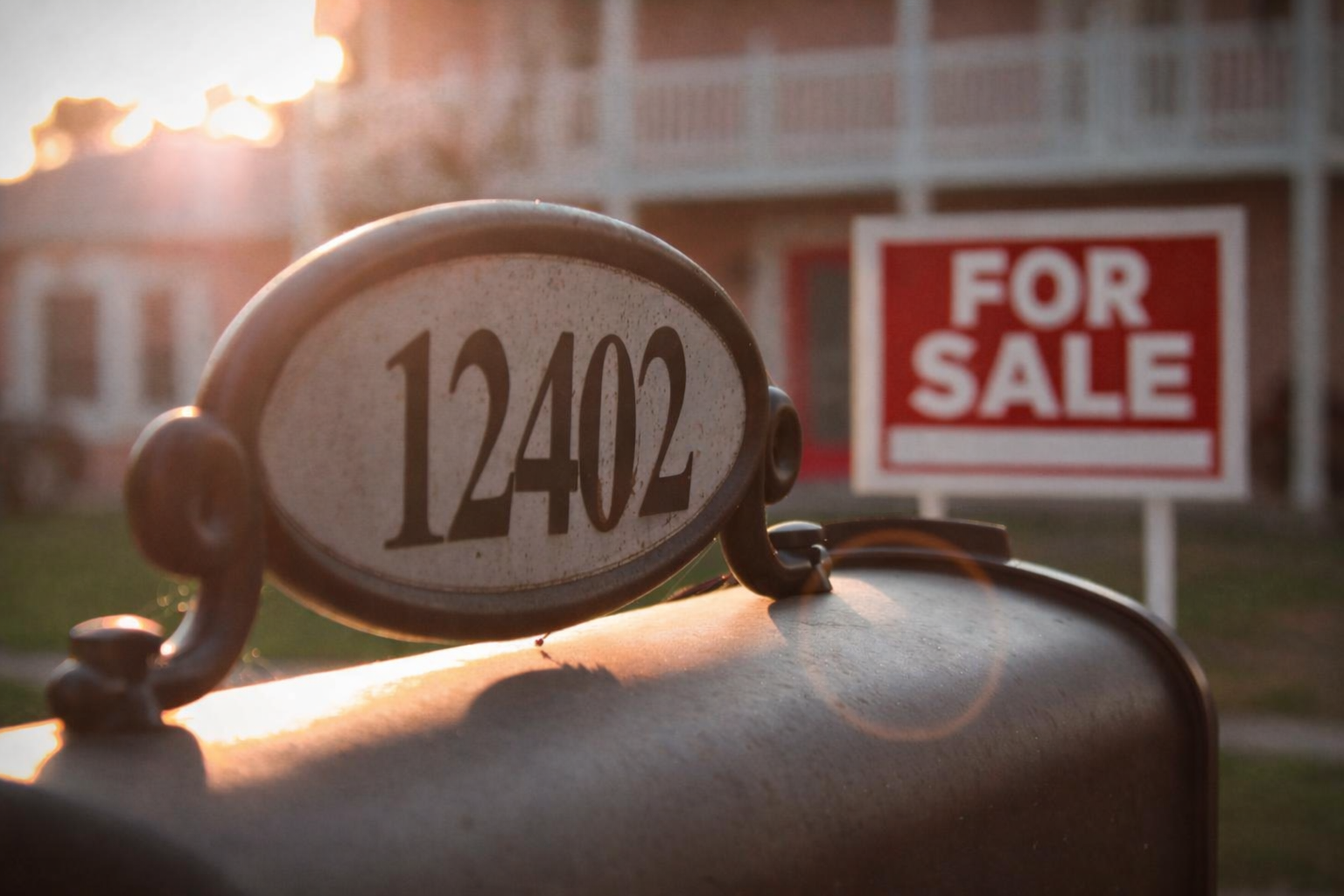 Mailbox with house number 12402 and real estate For Sale sign in front of Boulder, CO home with porch and white railings at sunset.
