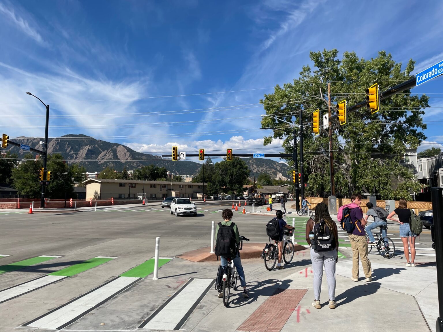A walkable Boulder neighborhood street scene — ideally a NoBo Broadway block or the Boulder Junction corridor showing outdoor seating, cyclists, and ground-floor retail.