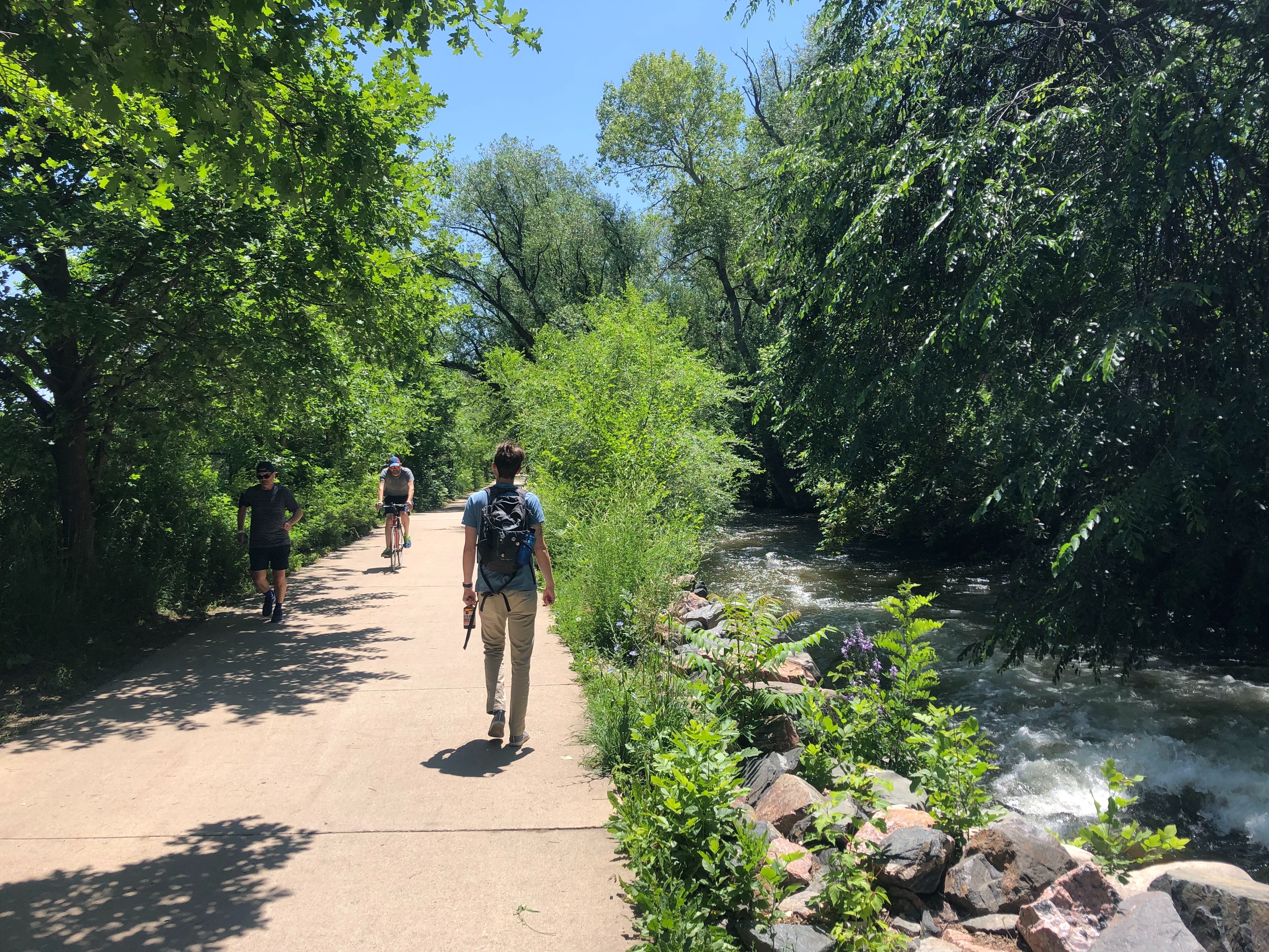 Goose Creek Trail multiuse path in East Boulder, Colorado with mountain views and joggers and hikers on a sunny day