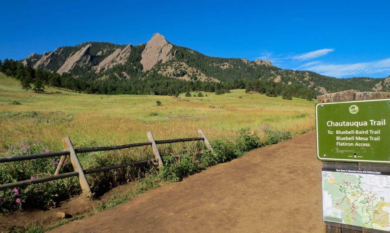 Chautauqua Park trailhead and Flatirons rock formations with hikers on a sunny day in Boulder, Colorado