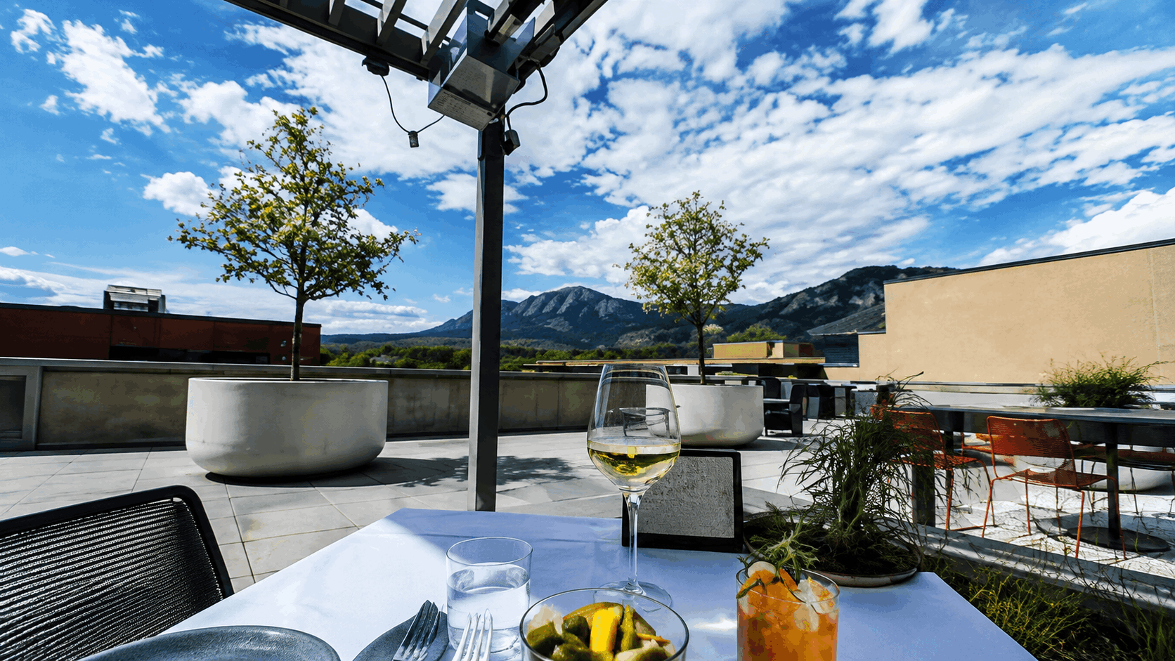 Outdoor rooftop dining in downtown Boulder with the Flatirons visible beyond the buildings