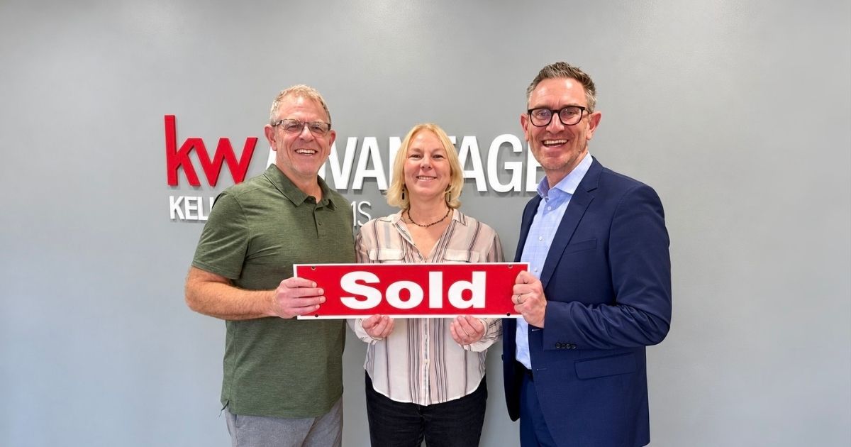 Three people celebrating a completed home sale while holding a red Sold sign at Keller Williams Advantage.