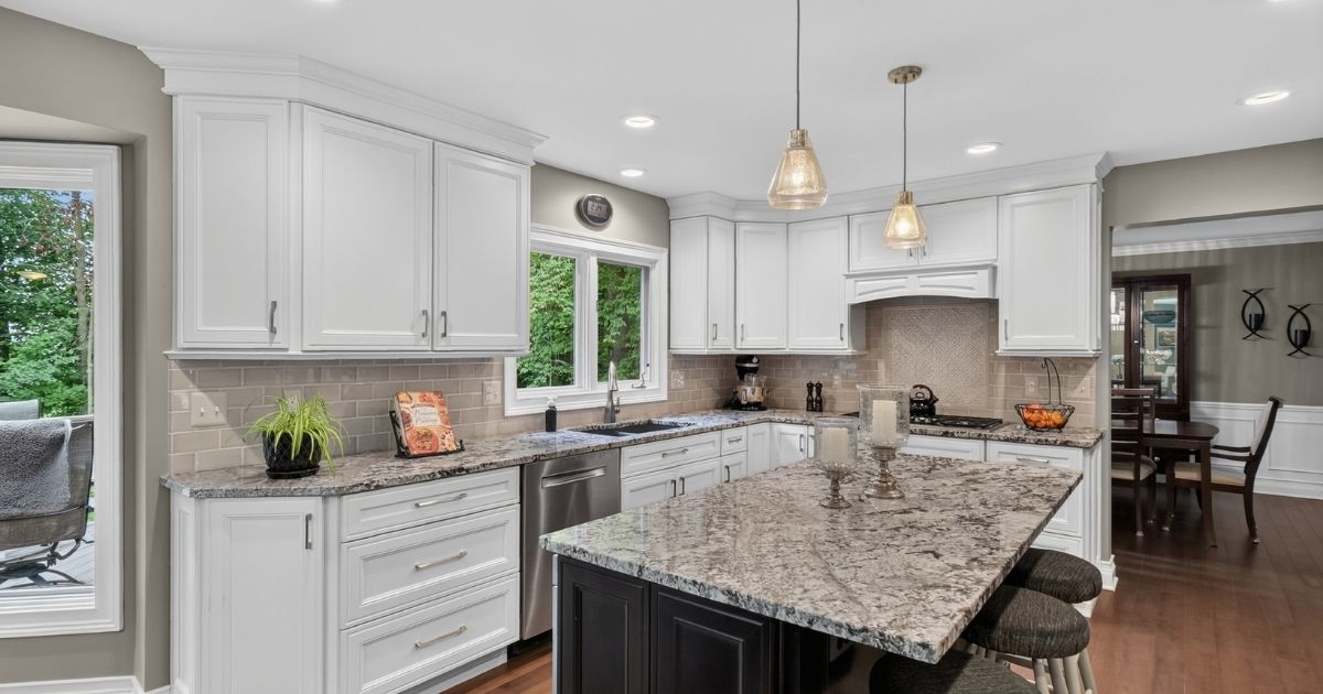 Additional view of the remodeled kitchen showing the large island, white cabinetry, pendant lighting, and adjacent dining space.