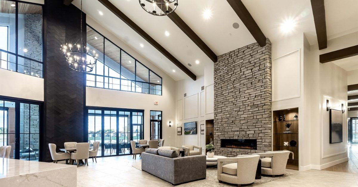 Great room inside The Lake House clubhouse at Kensington Ridge, with a stone fireplace and vaulted beamed ceiling