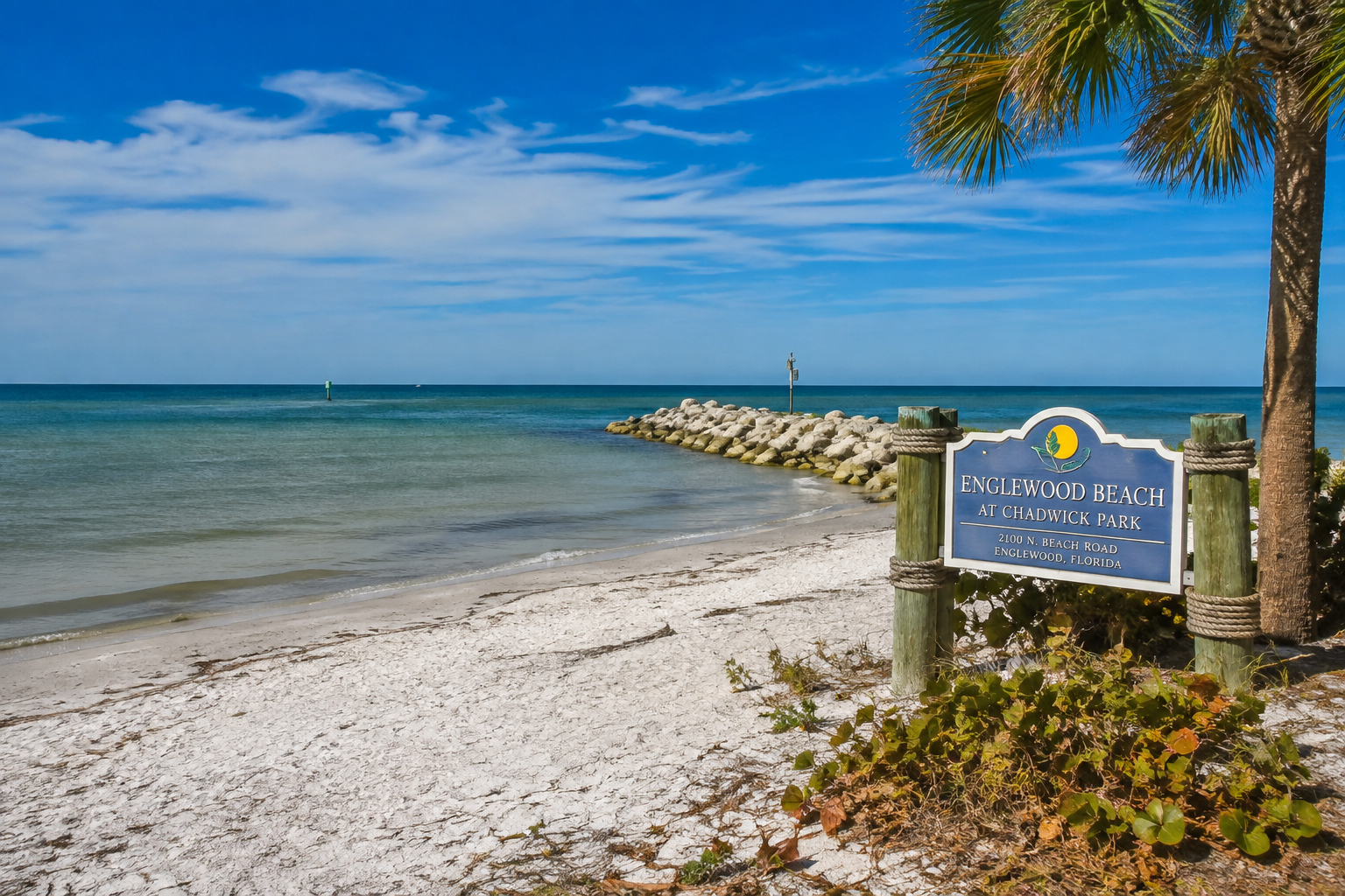 Englewood Beach at Chadwick Park sign with the Gulf, jetty and a palm tree