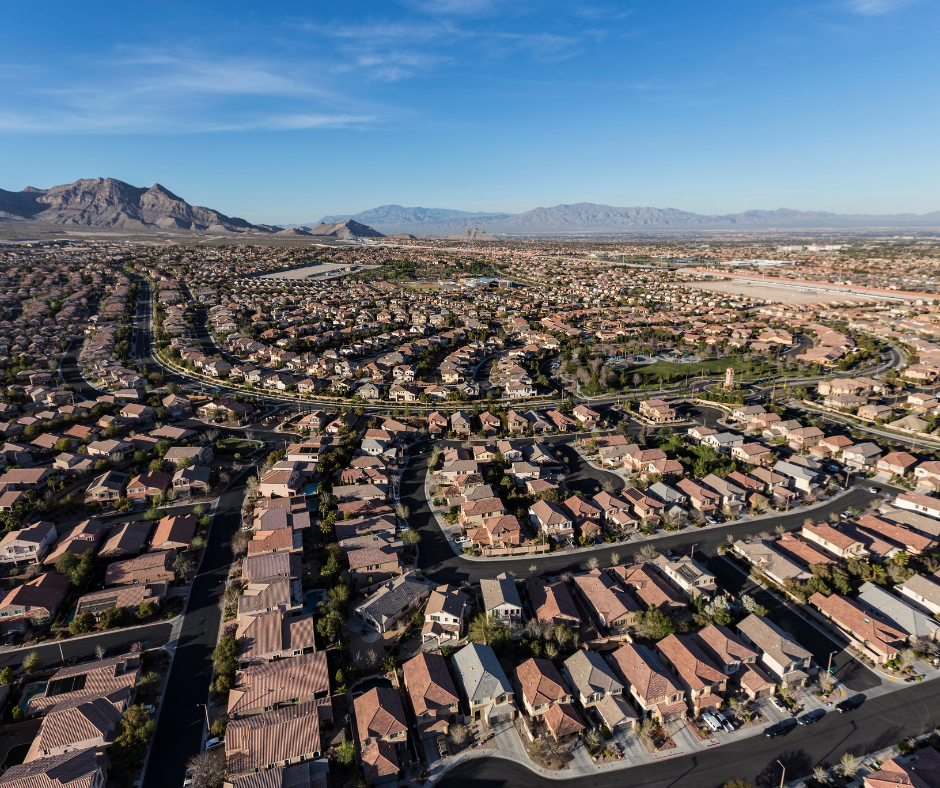 Aerial view of Mesa Arizona neighborhood with modern homes, tree lined streets, and mountain backdrop, representing Mesa real estate options. 