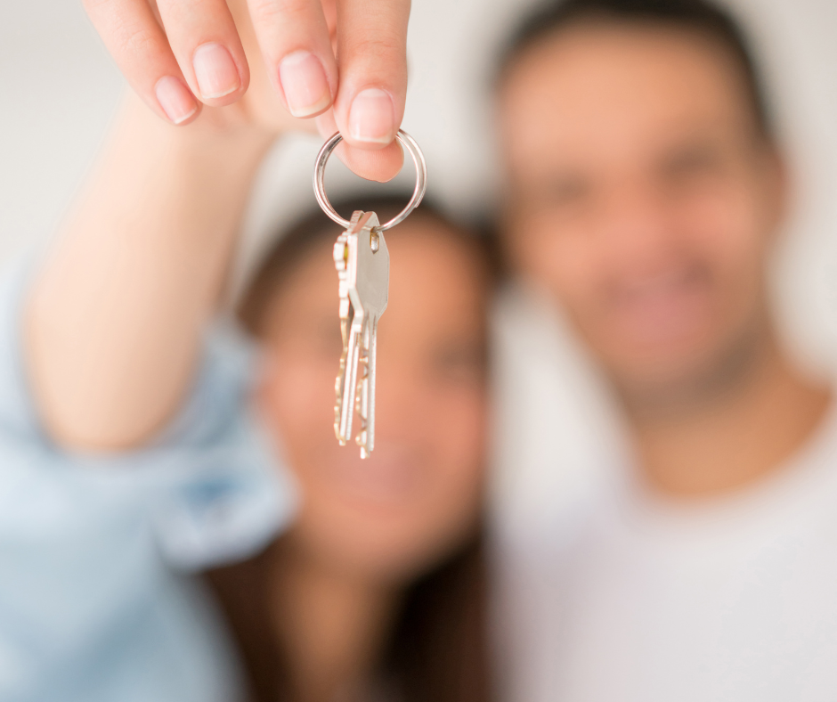 Happy first-time buyers in Mesa Arizona holding new house keys after purchasing their first home. 