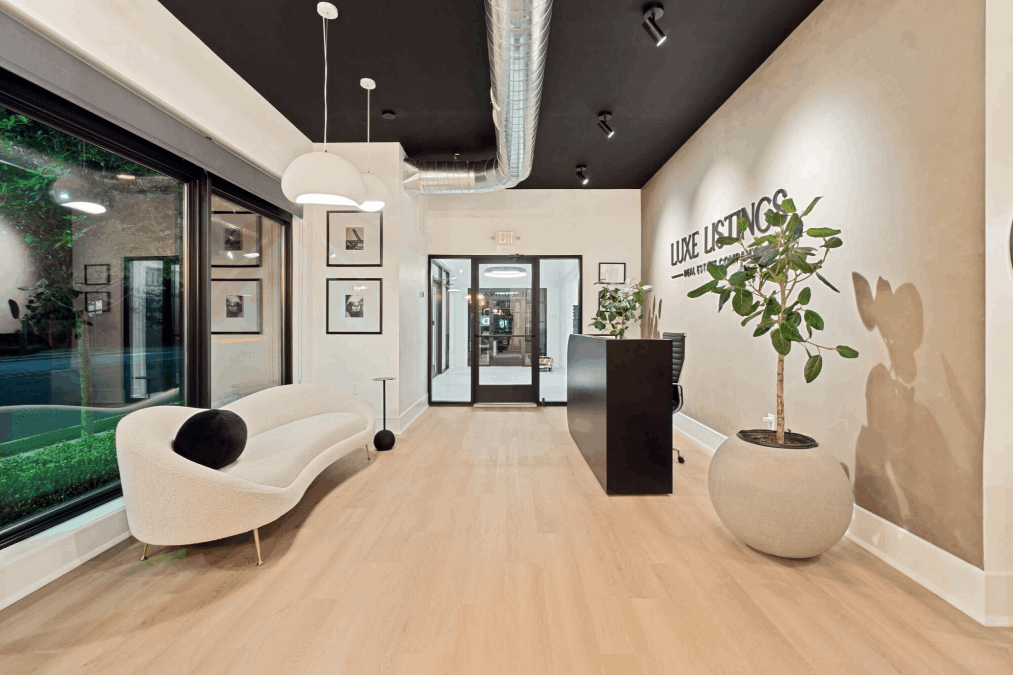 Photo of a modern office interior with a curved couch, large window and potted plants; aspect ratio approx 3:2