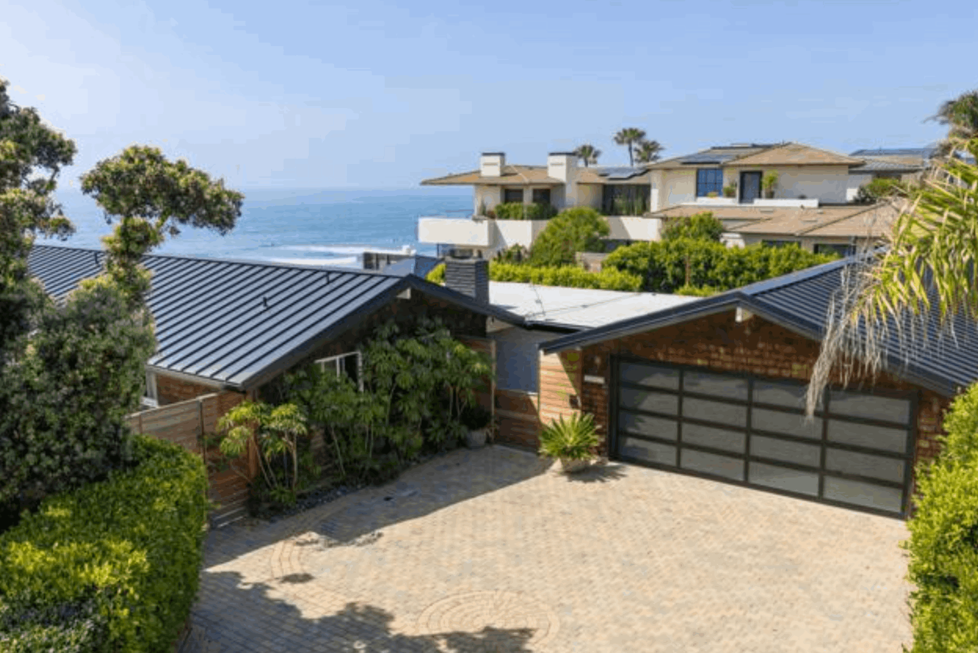 Luxury oceanfront home for sale in Terramar Carlsbad CA with a paved driveway and modern glass garage door