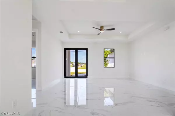 Cape Coral new construction living room with tray ceiling, large tile floors, and natural light