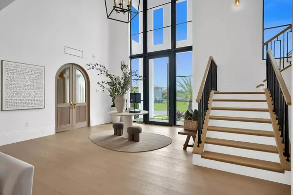 Luxury foyer at 839 Chestnut Court Marco Island with white oak floors, custom staircase, and arched solid white oak doors leading to private office