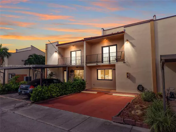 Front exterior of Sweetwater Miami townhouse at 11217 SW 1st St #5 featuring two stories, balcony, and driveway parking at sunset.