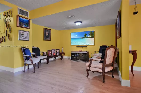 Opposite side of living room in Sweetwater Miami townhouse at 11217 SW 1st St #5 featuring PVC flooring, spacious layout, and entertainment area with mounted TV.