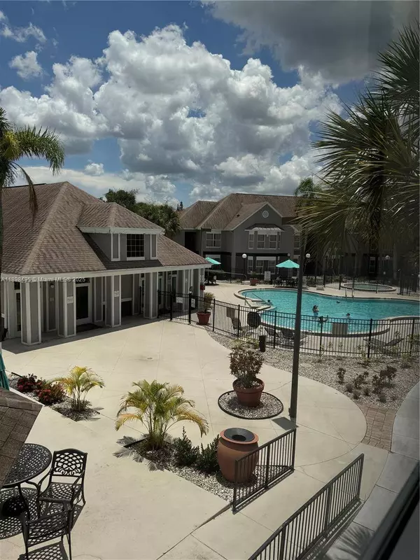 Resort-style pool area at Kissimmee condo for sale near Disney World with palm trees and lounge seating