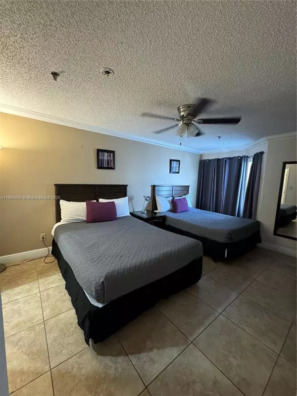 Spacious bedroom in Kissimmee condo for sale near Disney World with two beds and tile flooring.