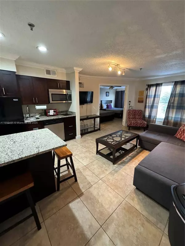 Open-concept kitchen and living area in Kissimmee condo for sale near Disney World featuring granite countertops and tile floors.