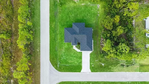 Overhead drone view highlighting the modern roofline, driveway, and landscaped corner location.