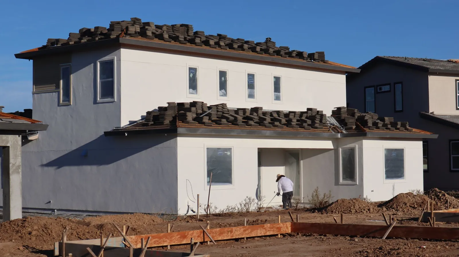 New home under construction with stacked roof tiles and fresh white stucco walls