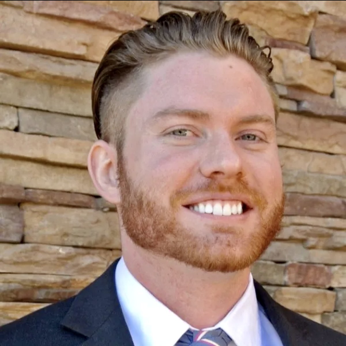 Nate Smith, REALTOR®, smiling in front of a stone wall