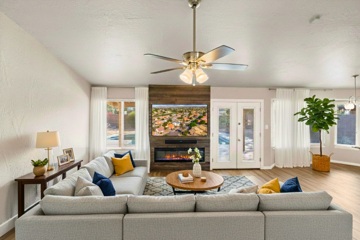 Open living room with vaulted ceilings in a Mesa Arizona home, featuring a custom entertainment center with electric fireplace, modern ceiling fan, and bright natural light—ideal for primary living or short-term rental use.