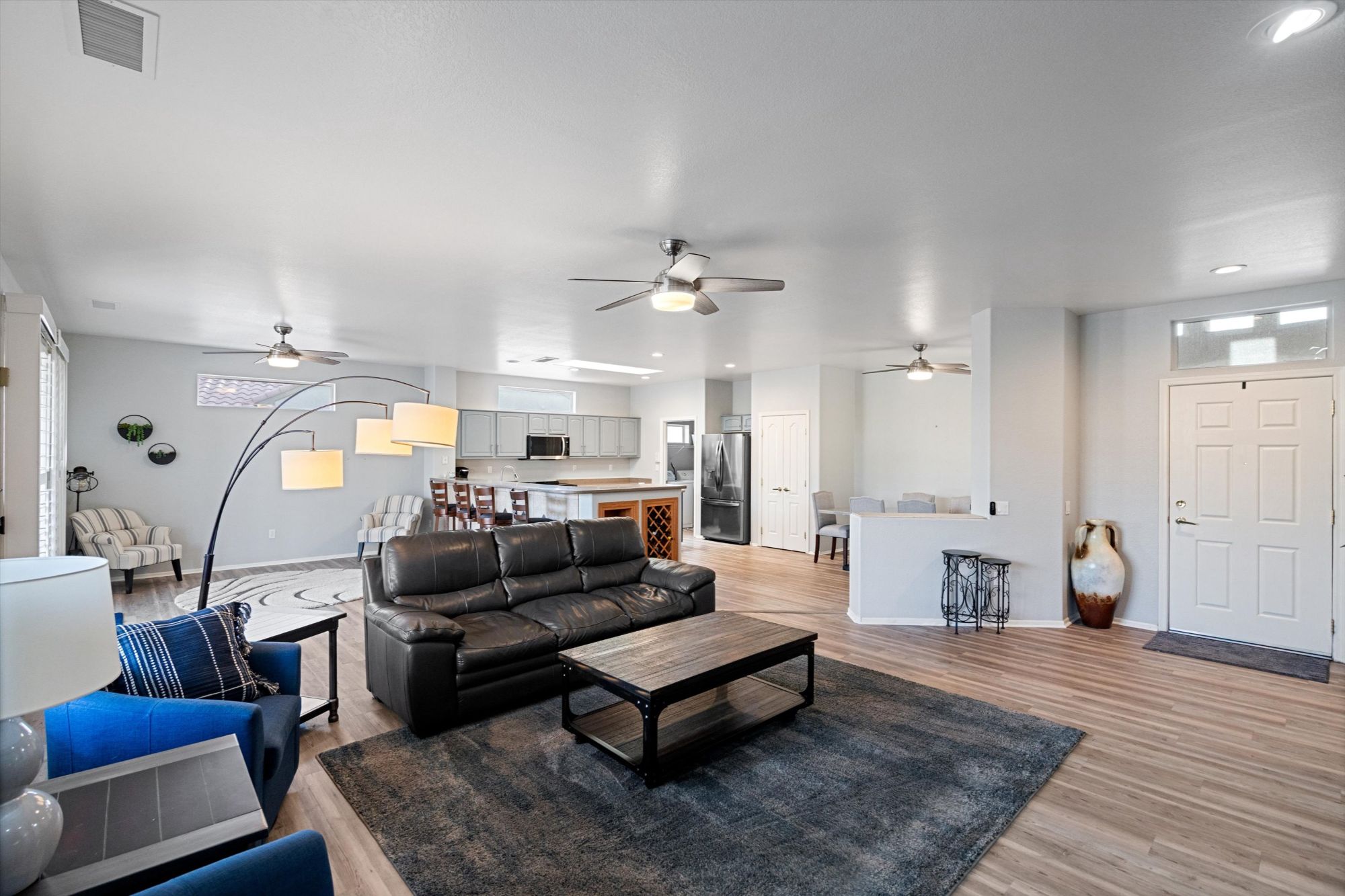 Open-concept great room inside a Cholla model home in Sun City Grand, Surprise AZ, featuring upgraded wood-look flooring, spacious living and dining areas, large windows with natural light, and an adjacent office/den—ideal layout for 55+ active-adult living.