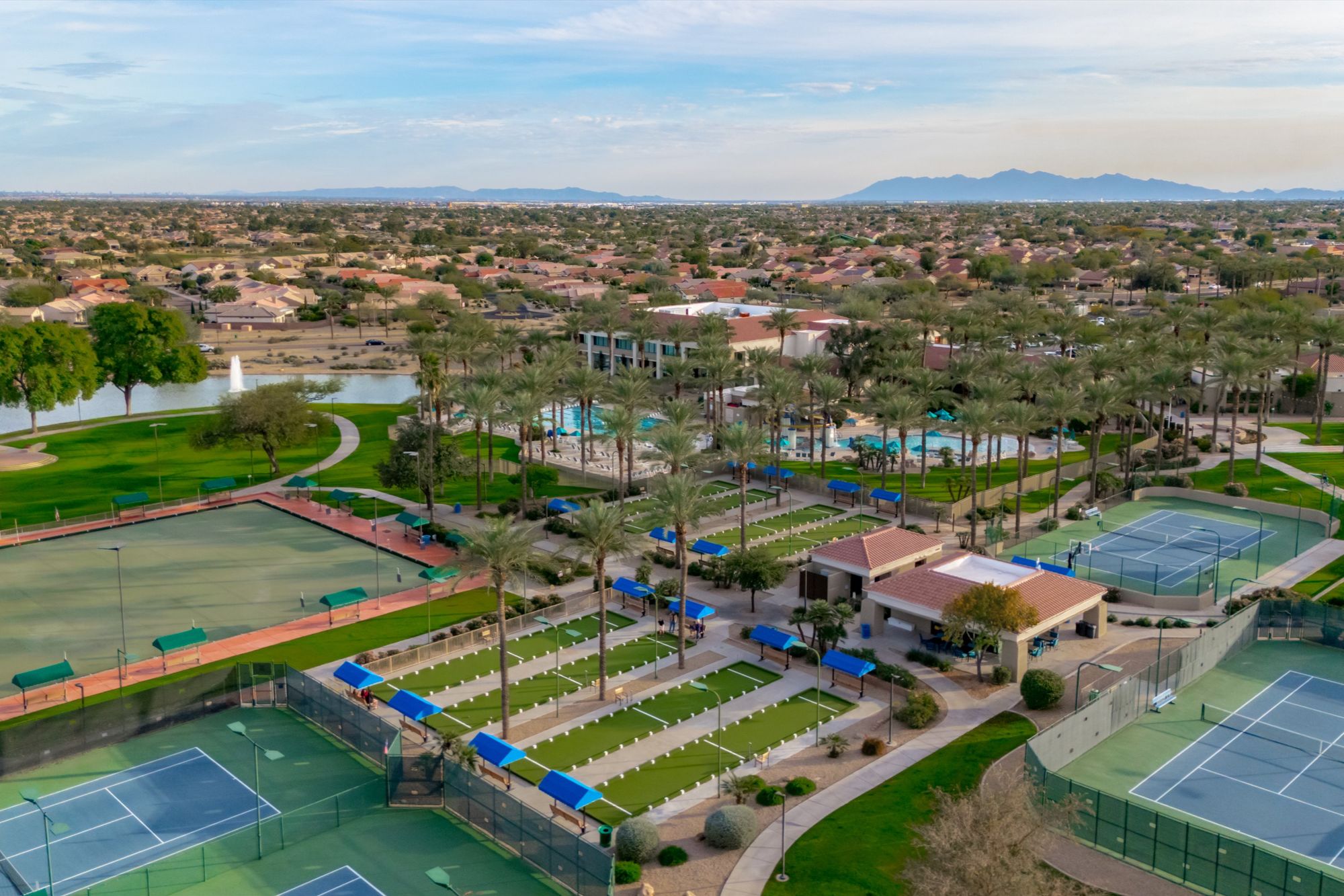 Aerial view of Sun City Grand in Surprise, Arizona, highlighting resort-style recreation amenities including pickleball and tennis courts, landscaped green spaces, walking paths, and clubhouse facilities within a premier 55+ active-adult community.