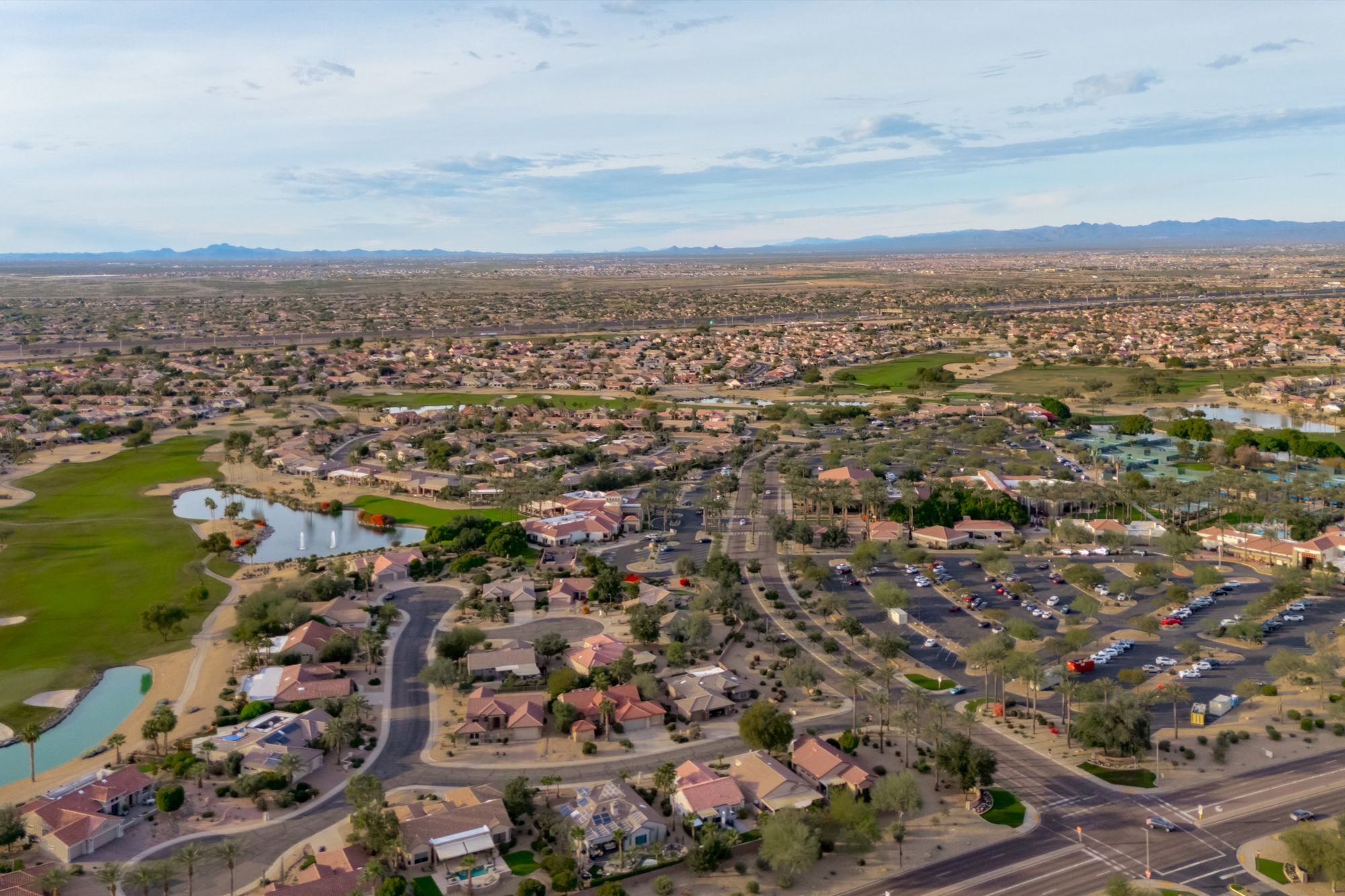 Aerial view of Sun City Grand in Surprise, Arizona, featuring championship golf courses, scenic lakes, clubhouse amenities, and surrounding homes within one of the West Valley’s premier 55+ active-adult communities.