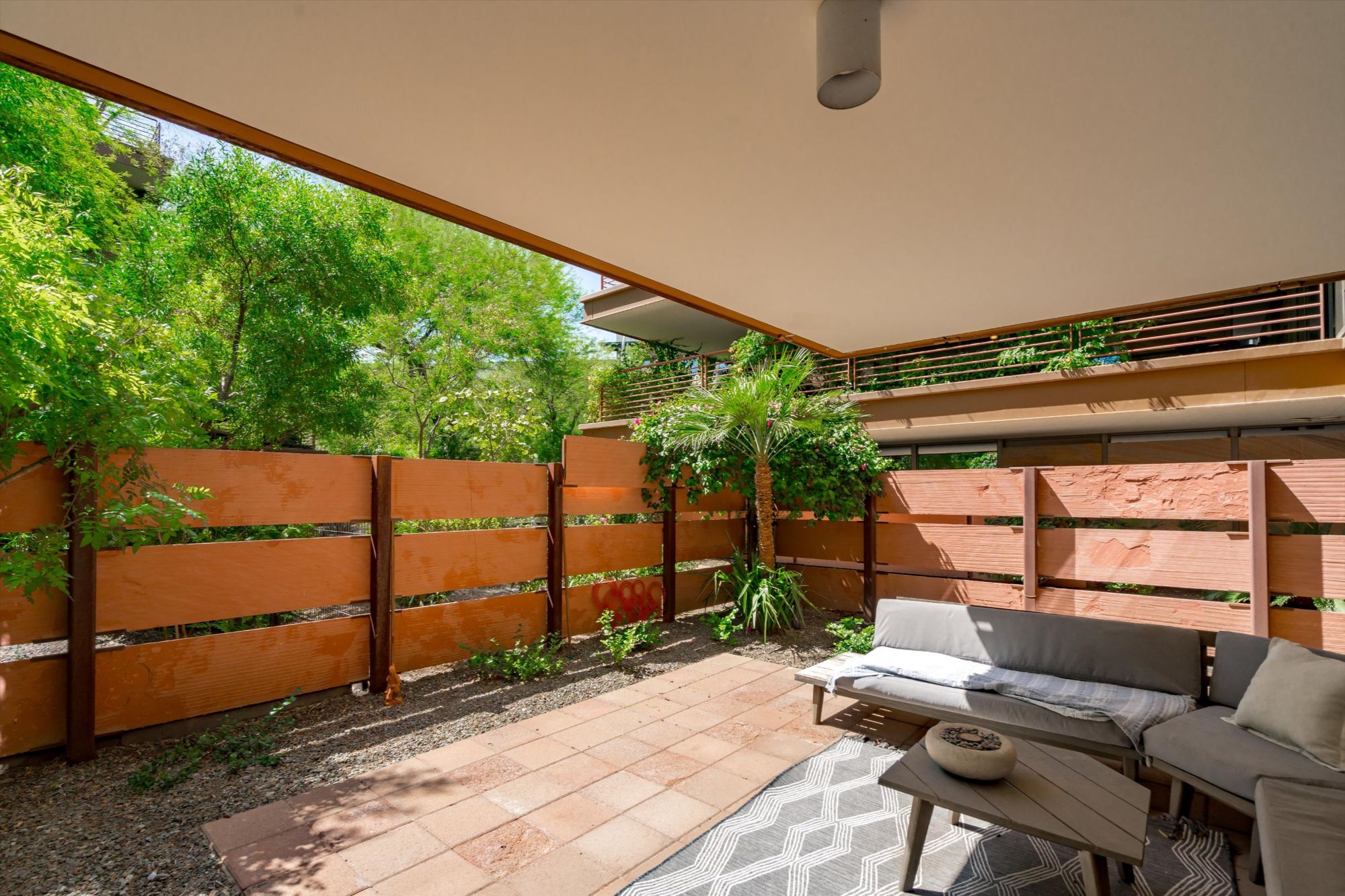 Shaded private patio at Optima Camelview Village condo in Scottsdale, AZ, featuring modern fencing, desert landscaping, and built-in seating. This rare ground-level outdoor space is ideal for entertaining or relaxing, located just minutes from Scottsdale Fashion Square and Old Town. The condo community offers luxury amenities, rental flexibility, and a walkable lifestyle in one of Scottsdale’s most desirable locations.