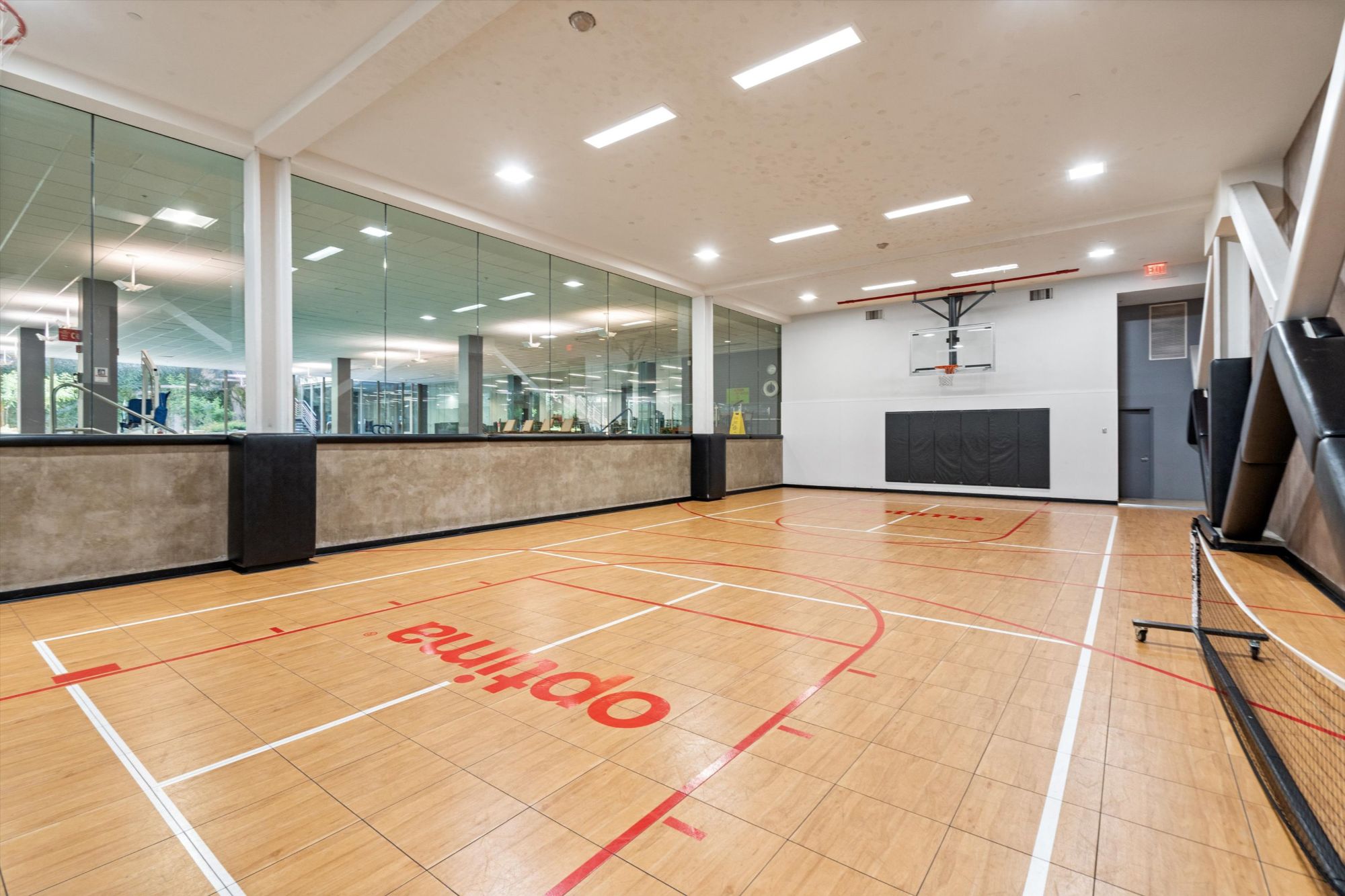 Indoor basketball court at Optima Camelview Village in Scottsdale, AZ, featuring polished wood floors and glass walls overlooking the community’s full fitness center. Part of the resort-style amenities available to residents, including pools, racquetball courts, concierge, and on-site restaurant. Located near Scottsdale Fashion Square and Old Town, with rental-friendly ownership options.