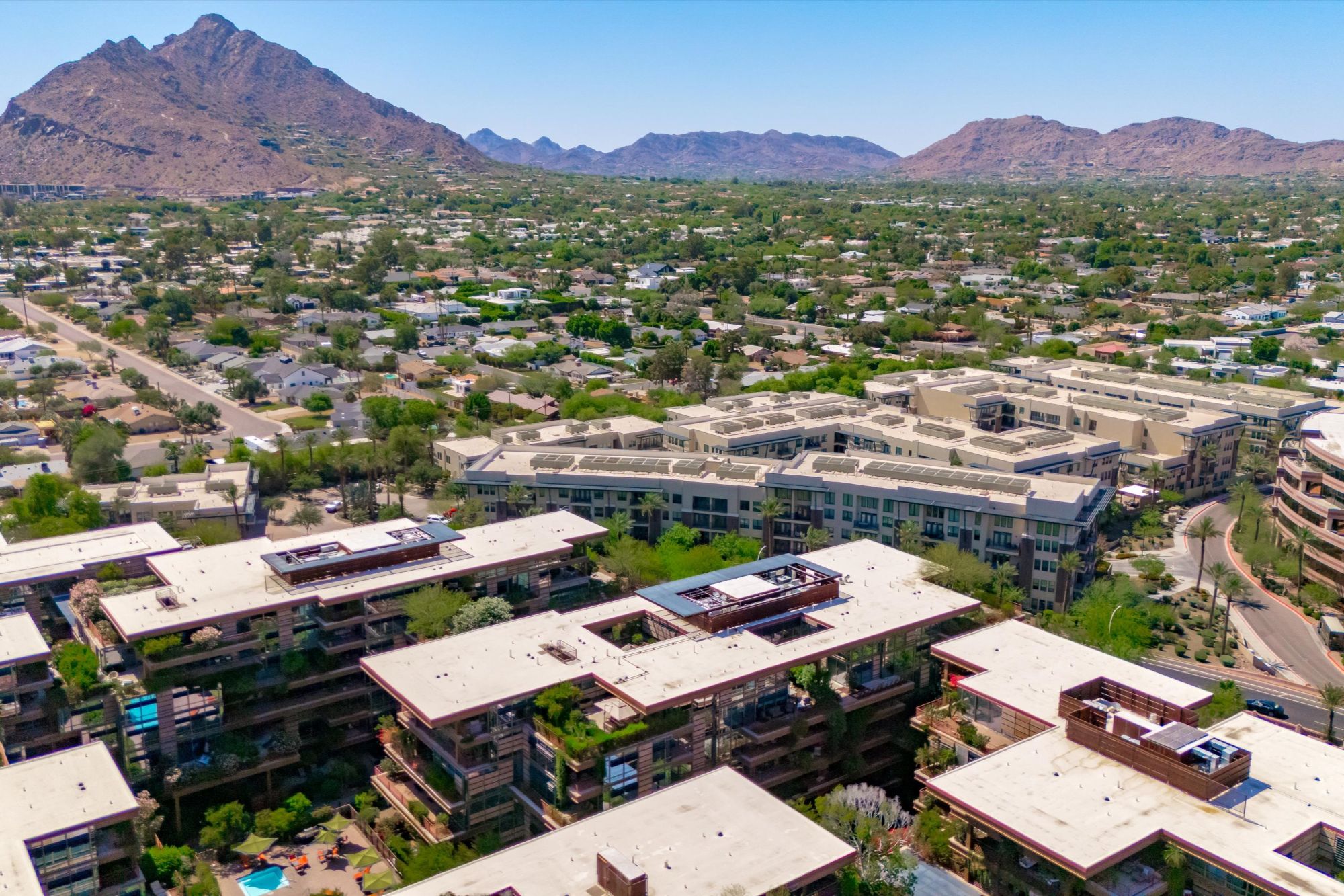 Aerial view of Optima Camelview Village luxury condos in Scottsdale, AZ, featuring rooftop gardens, resort-style amenities, and mountain views—located near Scottsdale Fashion Square and Old Town. This community offers rental investment opportunities, walkable living, and access to indoor/outdoor pools, fitness center, on-site restaurant, and concierge services.