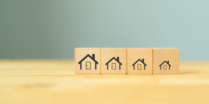 Progressively smaller house icons on wooden blocks representing the downsizing process — featured cover image for blog on how downsizing your home can unlock financial freedom and fund retirement goals.