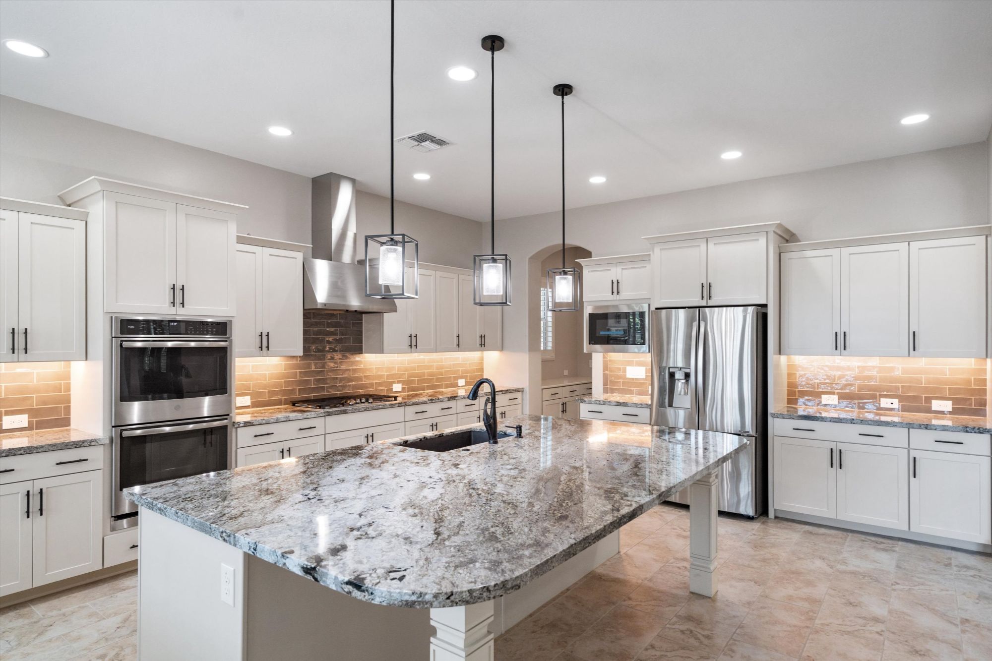 Chef's kitchen with white maple cabinets, granite counters and oversized island in a Victory at Verrado home for sale