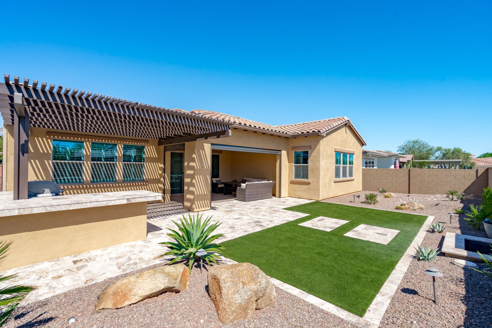 Private backyard with travertine, turf, built-in BBQ and White Tank Mountain views at 20947 W Mariposa St, Buckeye