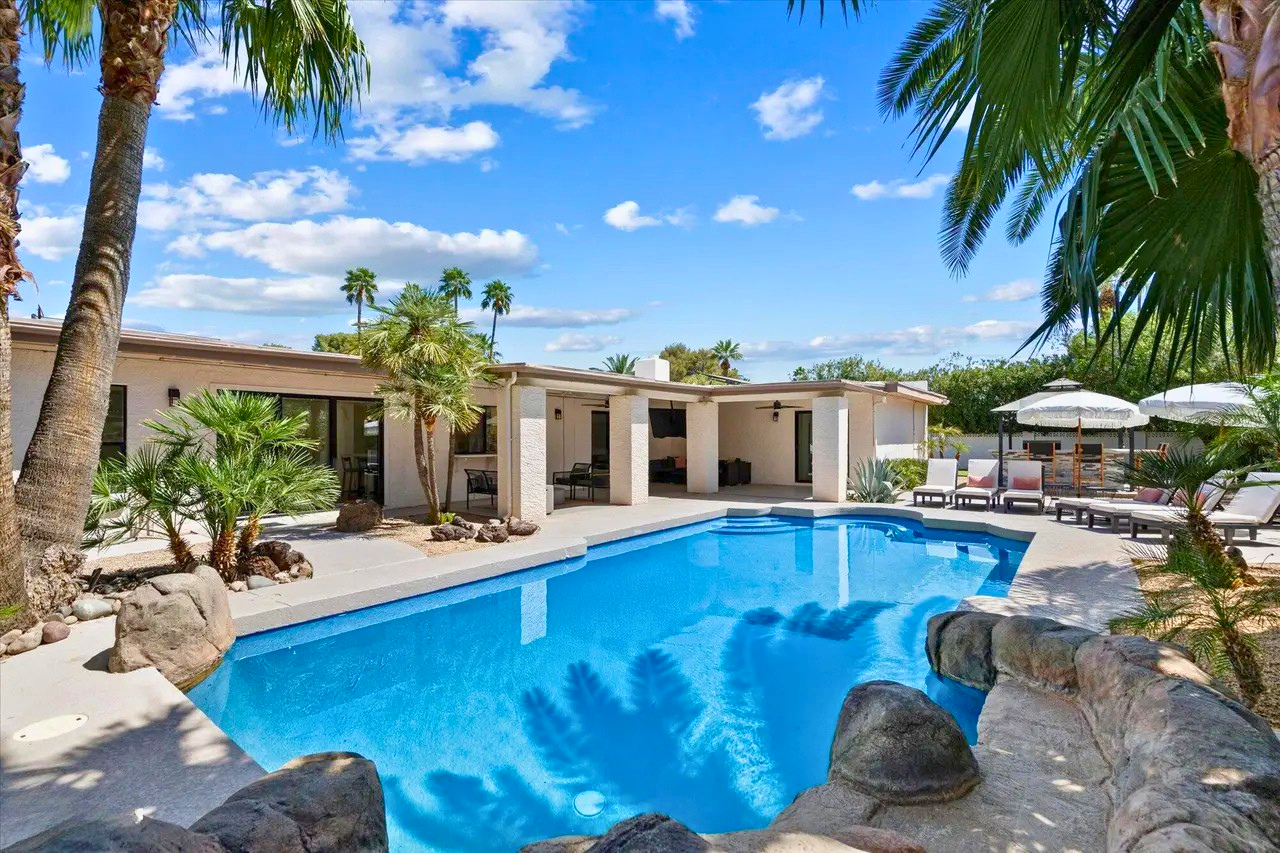 Resort-style backyard pool at a turn-key short-term rental property in Scottsdale 85254, featuring a heated pool, palm trees, and outdoor lounge areas designed for Airbnb guests