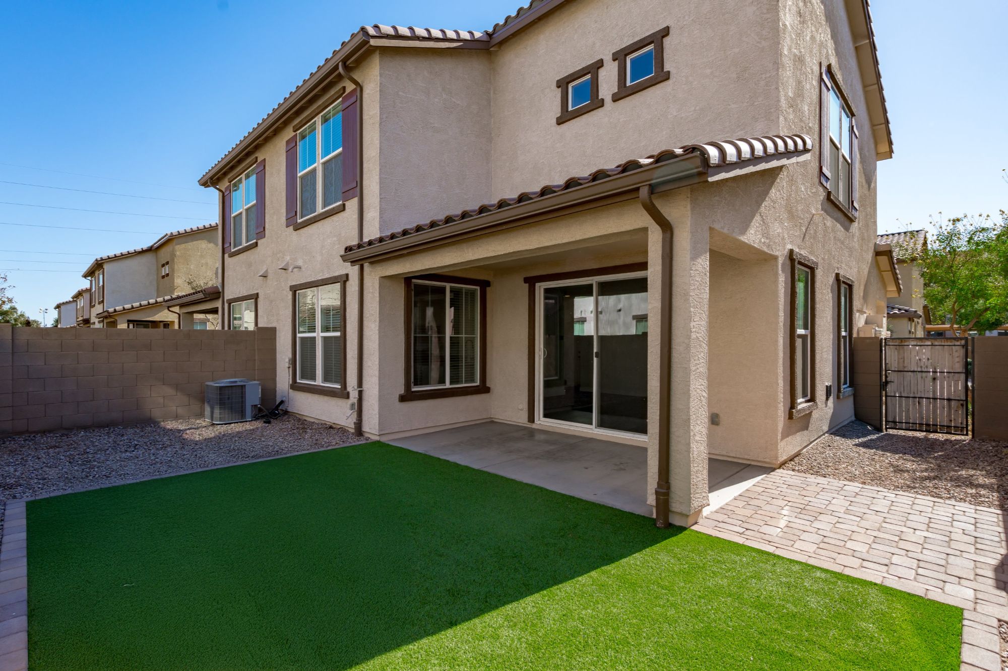 Private backyard of a gated townhome in Chandler, Arizona, featuring artificial turf, covered patio, paved walkways, and low-maintenance outdoor space ideal for lock-and-leave living.