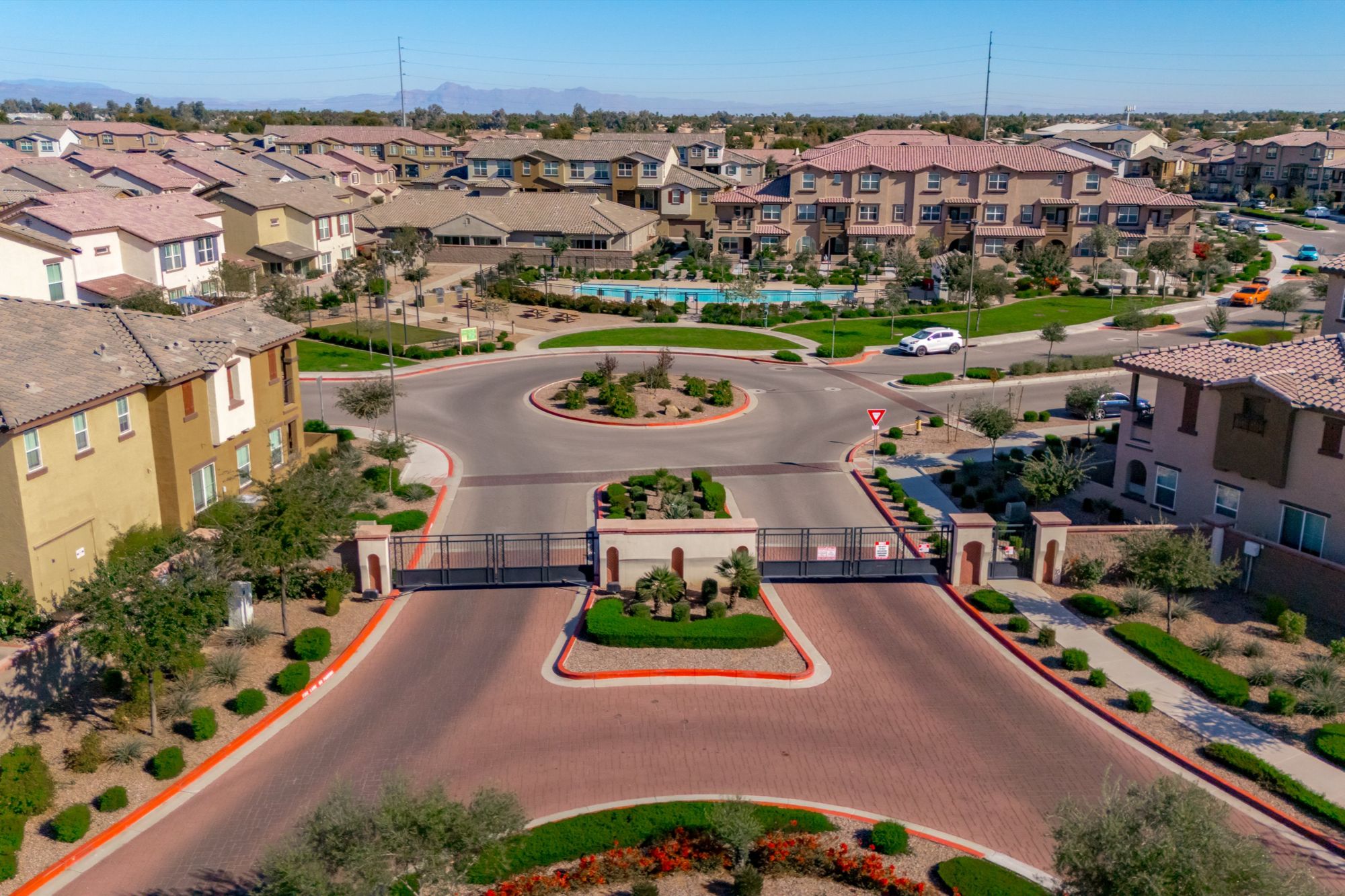 Aerial view of the gated entrance to a residential community in Chandler, Arizona, featuring controlled access, landscaped roundabout, and modern townhomes in a central East Valley location.