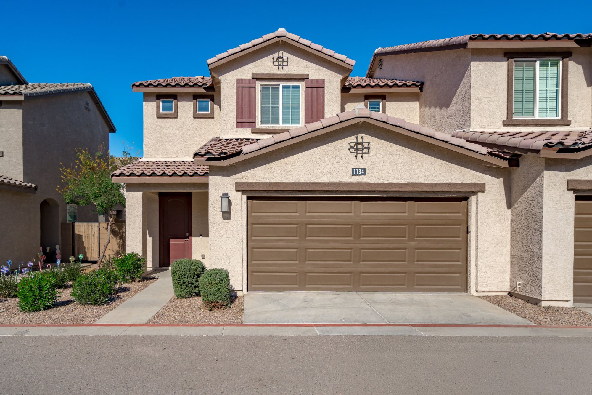 Front exterior of a modern townhome in a gated Chandler, Arizona community, featuring a two-car garage, stucco façade, tile roof, and low-maintenance desert landscaping in a central East Valley location.