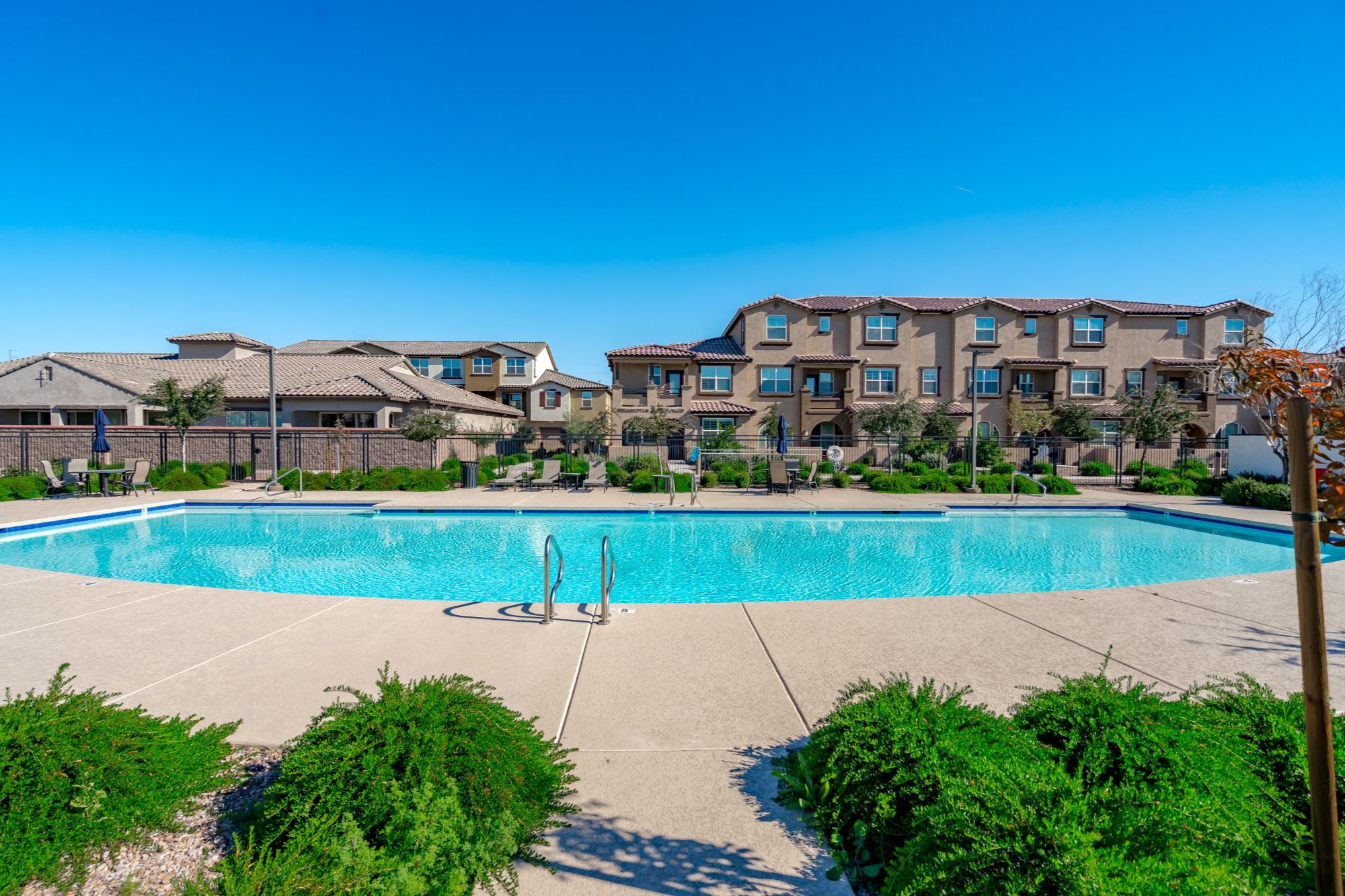 Resort-style community pool in a gated Chandler, Arizona townhome community, featuring landscaped surroundings, lounge seating, and shared amenities ideal for low-maintenance East Valley living.